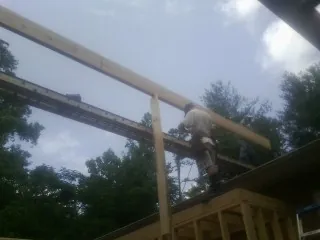 Carpenter setting a ridge beam over a new addition frame — Ice Dam Removal by Roofing Brothers in Norton