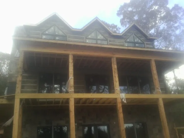 Dormers and porch framing on a large log home under construction — Roof Coating work by our crew in Norton