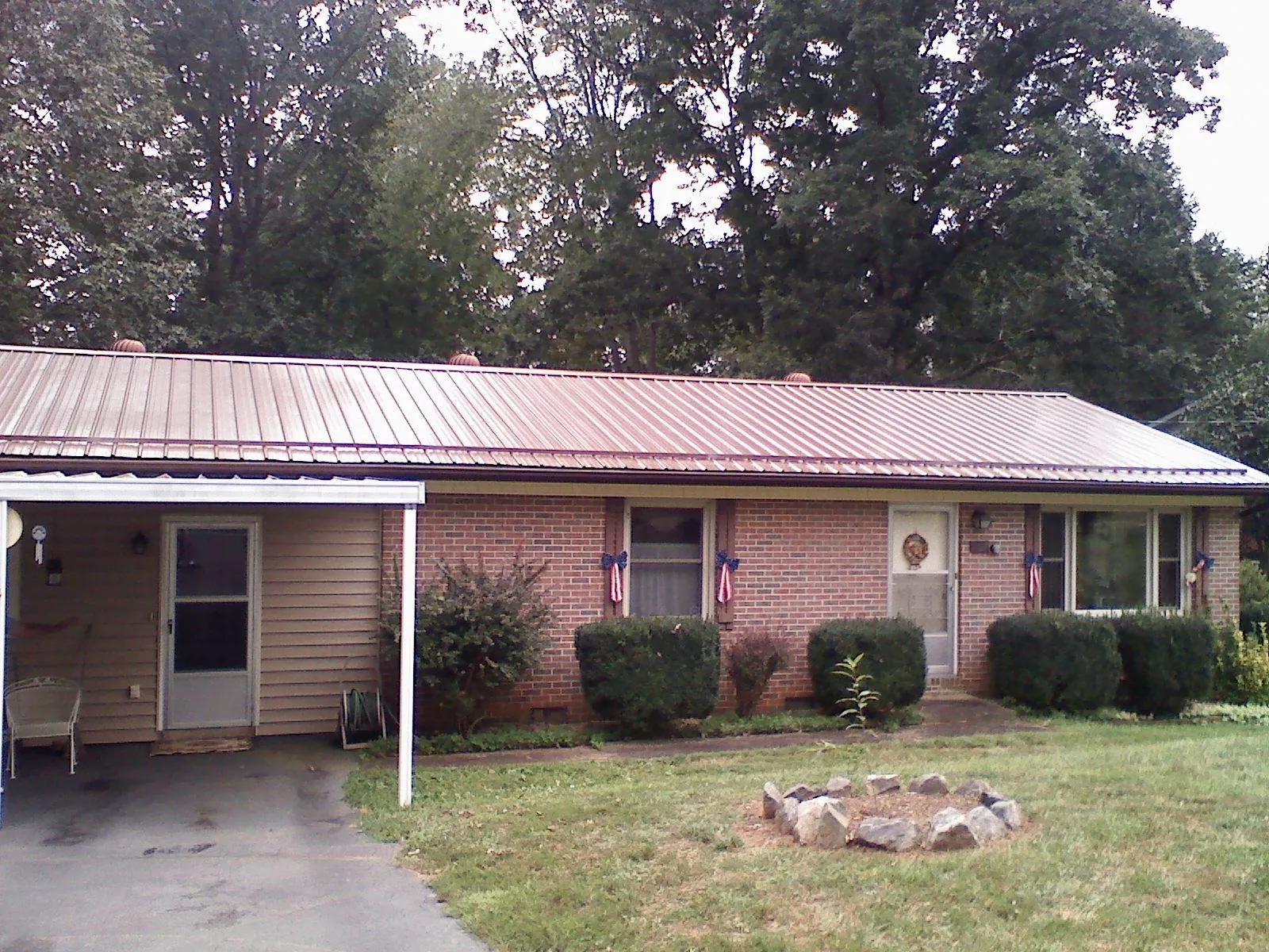 Bronze metal roof and carport on a brick ranch home — Roof Repair work by our crew in Norton