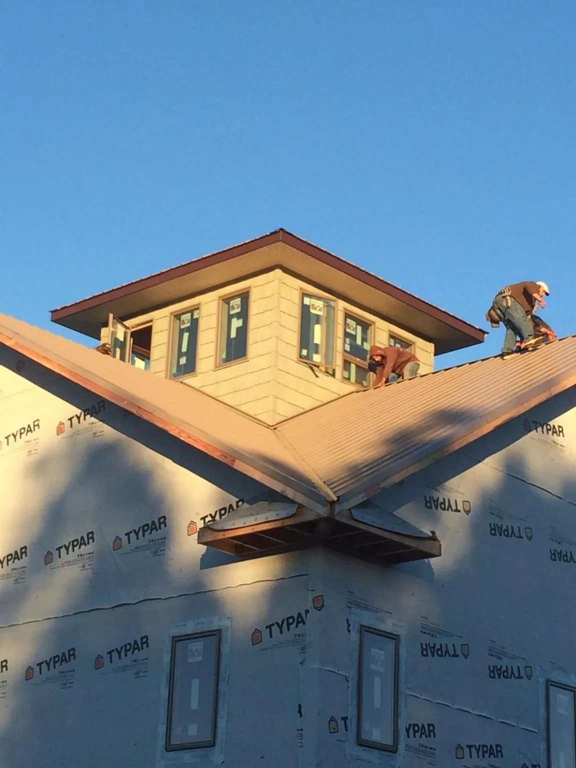 Roofers working around a rooftop cupola on a new metal roof at sunset — Roof Waterproofing in Norton by Roofing Brothers
